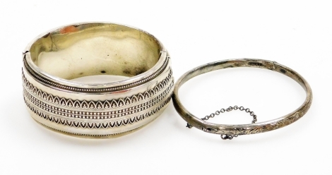 A hinged bangle, with applied filigree type decoration, white metal, stamped sterling, together with another thin silver hinged bangle, 55.4g all in.