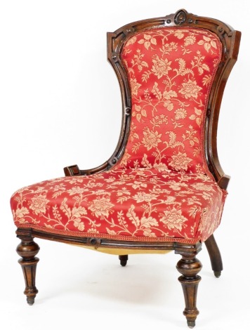 A Victorian mahogany framed nursing chair, upholstered in a red floral upholstery with floral engraved back, 73cm high, 61cm wide, 52cm deep.