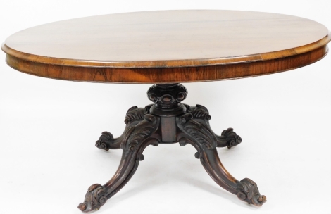 A Victorian rosewood breakfast table, the oval top with moulded border on a four leg base, the legs with rococo scroll carving terminating in castors, the top 111cm long, 142cm wide, 78cm high.