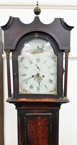 An early 19thC mahogany long case clock, with shaped hood and brass bulbous finials, on column supports above single door with marquetry shell carving, with an eight day movement, weights and pendulum, 216cm high, 47cm wide, 24cm deep.