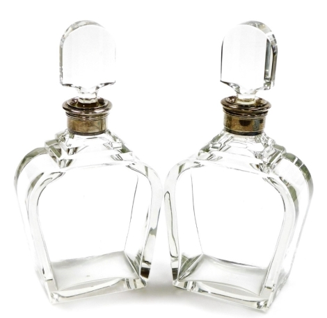 A pair of early George VI glass decanters, of heavy plain tapered design with stepped shoulders, the silver collars Birmingham 1937 and 1938, makers Pearce and Sons, with stoppers, 27.5cm high.