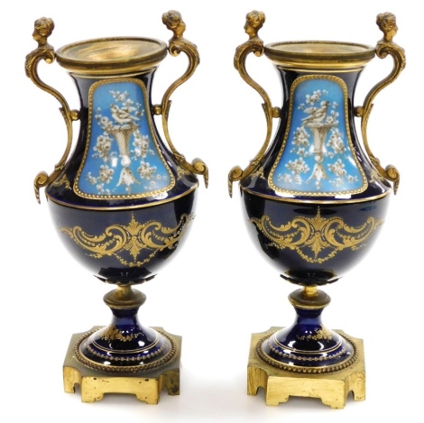 A pair of late 19thC vases, each with blue enamelled floral body, with birds and flowers, on brass base with figural handles, with HC stamp to underside, 27cm high, 12cm wide. (2)