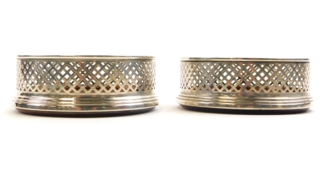 A pair of early 20thC pierced silver wine coasters, with a central silver shield, makers stamp B and Co Birmingham, with mahogany bases, 12cm wide.