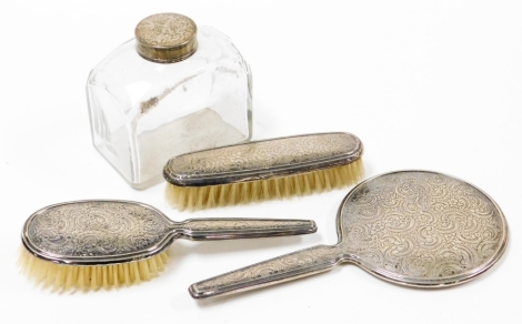 A group of silver and silver and silver plated dressing table items, to include a continental floral hand mirror and two brush set stamped 835, together with a cut glass dressing table jar, with a silver plated floral cap. (4)