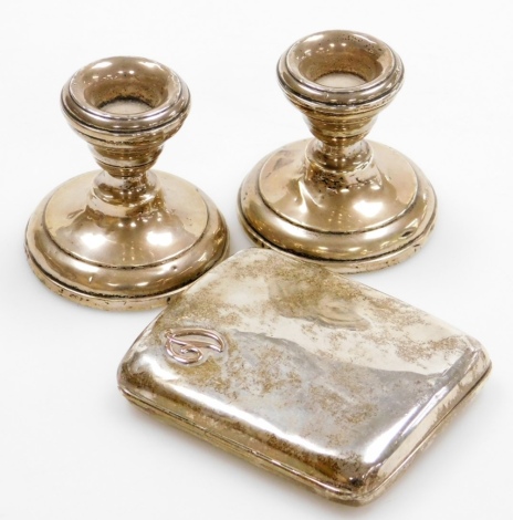 A group of small silver, to include a George V silver cigarette case, London 1917, baring silver gilt initial D, 3½oz, together with a pair of dwarf candlesticks, silver George V Birmingham, with weighted black bases. (3)