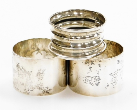 Three silver napkin rings, to include a pair of plain silver napkin rings makers stamp A and M, Birmingham 1982, and another of ribbed design, hallmarks rubbed, 3oz.