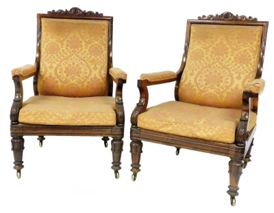 A pair of George IV rosewood library open armchairs, with scrolling cresting rails, padded backs and arms in Damask upholstery and loose seat cushions to match, with scroll arms and turned legs with brass castors. Provenance: Newbold Pacey Hall, Warwicksh