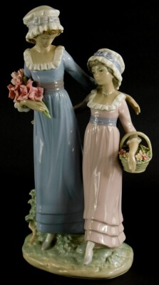 A Lladro porcelain figure group, of a lady with a young girl holding flowers, on oval base, 32cm high.