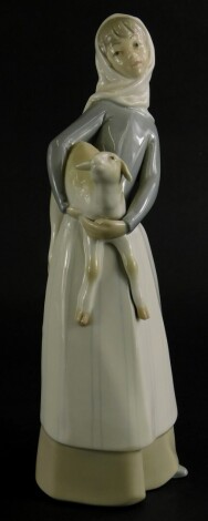 A Lladro porcelain figure of a lady holding a lamb, 27cm high.