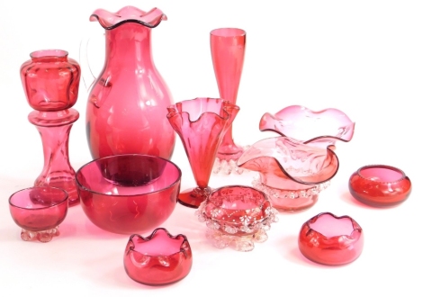 A collection of Victorian and later cranberry tinted glass, to include a vase modelled as a jardiniere and stand, two bowls with shaped borders, a finger bowl, a vase with a frilled base, salts, etc.