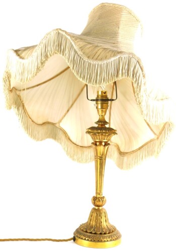 A continental gilt metal table lamp, cast with leaves on a tapering base, with decorative shade with metallic stitching, 57cm high overall.