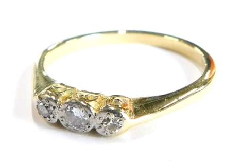 A three stone set dress ring, set with three tiny diamonds, in illusion platinum setting, with scroll design ring head on a yellow metal band, unmarked, ring size P½, 3.1g all in, boxed.