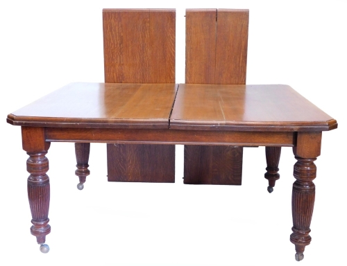 An oak extending dining table, the rectangular top with canted corners, two loose leaves, 73cm high, 118cm deep, 240cm long.