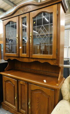 An oak dresser, the top with two leaded glazed doors, the base with two hinged doors.