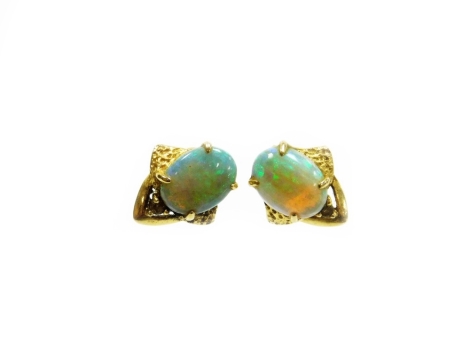 A pair of opal earrings, each set with oval opal in four claw setting, with tiny diamond top, and abstract hammered design back, in yellow metal with butterfly backs, unmarked, 2g all in, 1cm high.