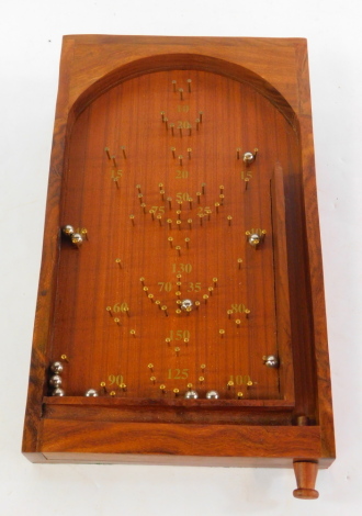 A wooden table top bagatelle, with balls.