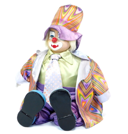 A porcelain figure of a seated clown, with painted face and garish silk clothing, 35cm high.