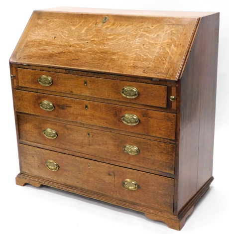 A George III oak bureau, the fall enclosing a vacant interior above four graduated drawers, each with oval brass handles, on short bracket feet, 99cm wide.