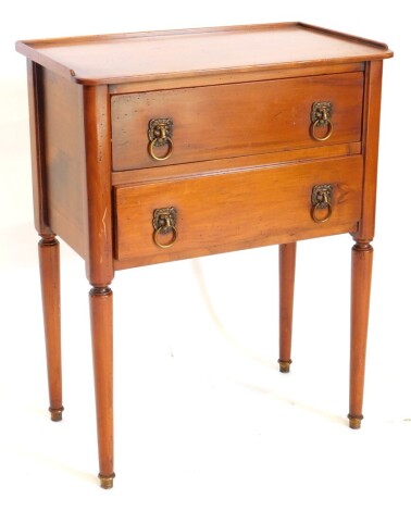 A French fruitwood bedside table, with a raised gallery, above two drawers, each with lion mask handles on turned tapering legs, 56cm wide.