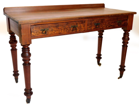 A Victorian pitch pine side or writing table, with a raised back above two frieze drawers, each with angular handles, on turned legs with ceramic castors, 81cm high, 121cm wide.