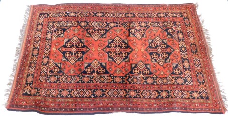 An Afghan rug, with a design of medallions and geometric devices on an orange ground, one wide and various narrow borders, 195cm x 125cm.