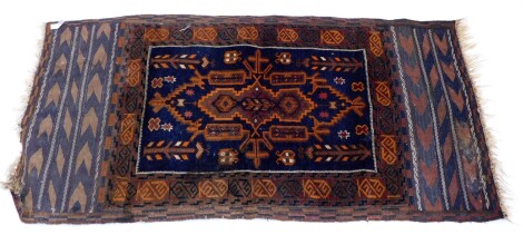 A Belouch rug, with a central medallion in orange, brown, etc., on a navy ground with one wide border and flat weave ends, 150cm x 82cm.