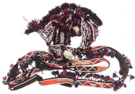 A Persian flatweave horse harness and reins, with woven carpet section, embellishments with buttons, coloured fabrics and tassels, 200cm x 50cm approximately.