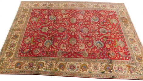 A Persian Tabriz type carpet, with an all over design of flowers, leaves etc., on a red ground with one wide and two narrow borders, 192cm x 208cm.