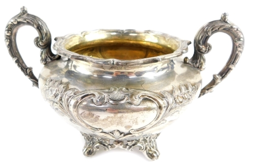 A William IV Scottish silver sugar bowl, of twin handled form, with shield reserves, embossed framed with flowers and rococo scrolls, one presentation engraved 'Presented to John Coutts Esq., Surgeon, Fraserburgh, 20th June 1839', raised on four leaf scro