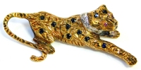 A 9ct gold leopard brooch, the body set with various sapphires, with a tiny diamond set white gold collar and ruby eyes, 5cm wide, 6.9g all in.