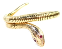 A 9ct gold snake articulated bracelet, with a steel internal spring, the head set with two garnet eyes, 5.5cm wide, 21.2g all in.