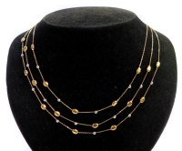 A three strand necklace, with decorative design of gold and silvered coloured balls, on a fine link chain, yellow metal stamped 9kt, 41cm long, 7.7g.