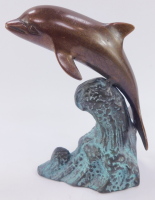 A bronze and patinated figure of a dolphin, riding the crest of a wave, 16cm high.