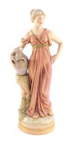 An early 20thC Royal Dux blush porcelain figure of a Roman lady, modeled standing with her arm around an amphora, raised on a circular base, pink triangle and impressed marks, 36cm high.