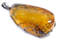 A large amber pendant, the amber with a rough applied backing, in a wire work white metal frame stamp 925, 9cm high, 4cm wide.