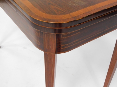 A George III rosewood and satinwood cross banded demi lune fold over card table, raised on tapering square legs, brass capped on castors, 73cm high, 91cm wide, 46.5cm deep. - 3