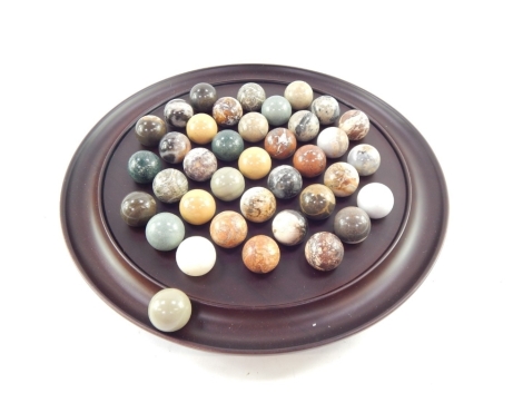 A polished treen solitaire board, with marble polished piece of large form, the board 33cm diameter.