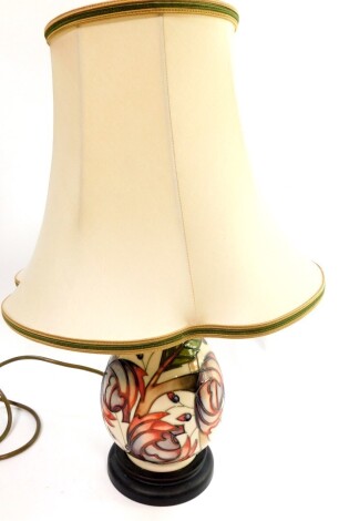 A Moorcroft pottery table lamp decorated with flowers, against a cream ground, of baluster form with shade, 45cm high.