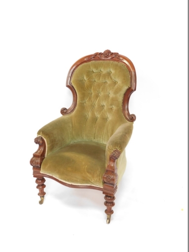 A Victorian carved mahogany open spoon back armchair, with studded back, plain arms and serpentine seat, heavily carved with flowerheads and fruits to the curved top rail, with heavily carved inverted arms on triple turned legs terminating in castors, 112