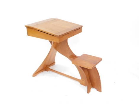 A 20thC one piece child's desk, with lift up lid raised above fixed seat, on a shaped base, 78cm high.