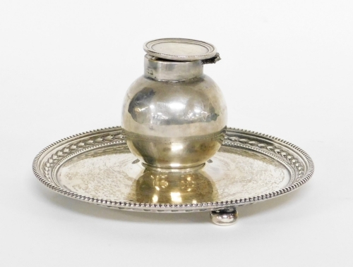 An Edward VII silver inkwell and stand, the bulbous shaped inkwell on a circular tray base, with fluted and ribbed borders, on three bun feet, makers stamp JD&S, Birmingham 1904 (AF), 7cm high, 13cm wide, 6½oz gross.