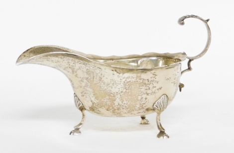 An Elizabeth II silver sauce boat, with fluted border, on rococo scroll handles, on tripod shell feet, Birmingham 1977, 4½oz.