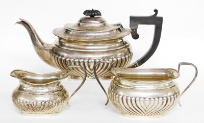 A George V silver three piece tea service, comprising teapot, milk jug, sugar bowl, the teapot with ebonised handle and knop, on a fluted body, Birmingham 1928, 39½oz gross.