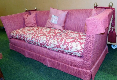 A Knole style three seater sofa, in a red upholstery, with brass acorn finials and ties, 80cm high, 225cm wide, 83cm deep.