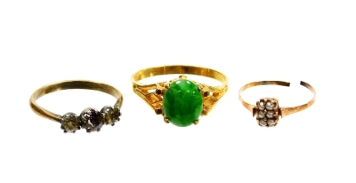 Three dress rings, to include a gold and seed pearl set dress ring, cut yellow metal unmarked, 0.7g, a silver and paste stone set three stone dress ring and a jade set dress ring, on a 18ct gold plated band. (3)