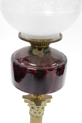 A late 19thC brass oil lamp, with a shade and reservoir, on a cranberry glass dome, on brass Corinthian column stepped base, 74cm high. - 2