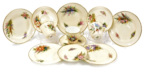 A Royal Worcester part tea service, decorated with various bright flowers on a cream ground, comprising three cups, four saucers and five side plates.