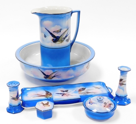 An Oxford 1950s/60s toilet set, comprising jug and bowl, dressing table set with candlestick and dressing table storage jars, decorated on a blue ground with blue tits and butterflies. (a quantity)