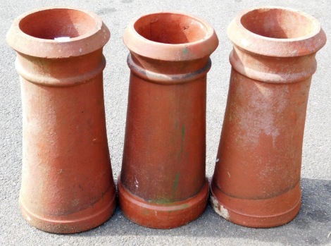 Three terracotta chimney pots, each of similar design, 63cm high, 63cm high and 62cm high.