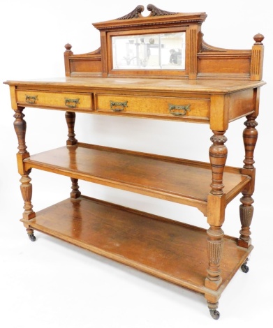 A Victorian oak three tier buffet, the back with mirrored panel on carved scroll top, above two drawers and two shelves on carved finial supports, 165cm high, 150cm wide, 57cm deep.